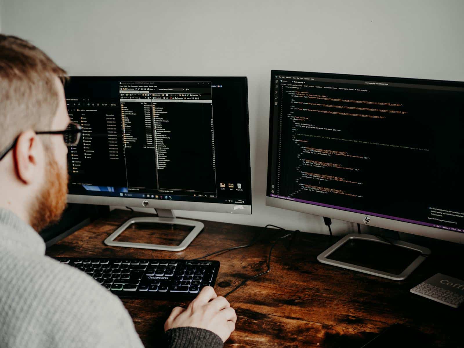 Een IT-beheerder werkt geconcentreerd achter meerdere computerschermen.