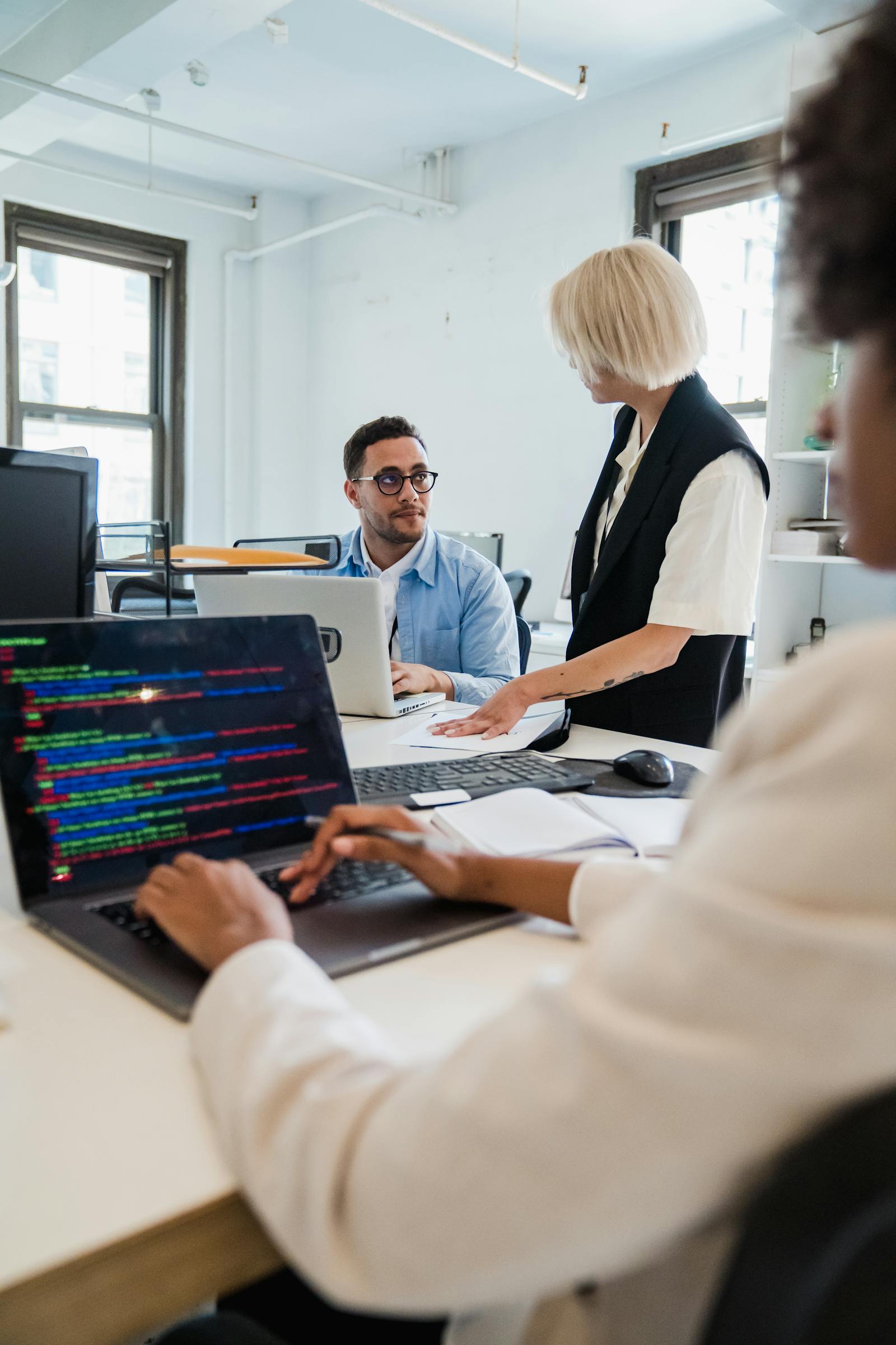 Collega's werken samen op laptops op kantoor.