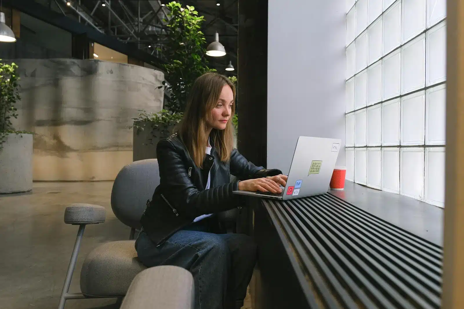 Iemand werkt geconcentreerd op een laptop in een lichte, moderne werkomgeving.
